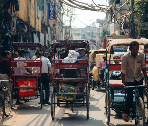 Persona montando una bicicleta en una calle concurrida de Delhi